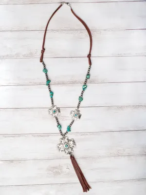 BOOTS, JEANS, TURQUOISE SILVER CROSS CONCHO WITH BROWN LEATHER TASSEL ON A NAVAJO PEARL NECKLACE